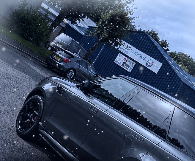 Grey Range Rover Sport in falling snow outside an industrial unit